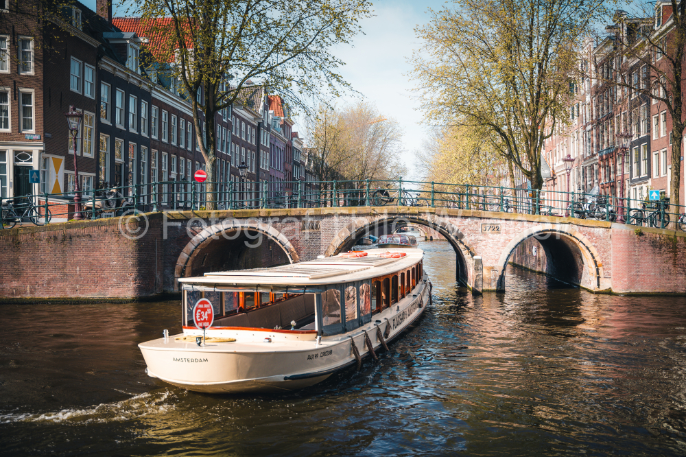 Amsterdam canal with cruise ship with Netherlands traditional house in Amsterdam, Netherlands. Landscape and culture travel, or historical building and sightseeing concept.