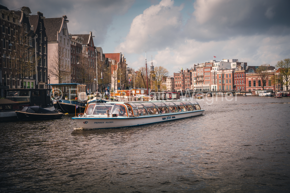 Amsterdam canal with cruise ship with Netherlands traditional house in Amsterdam, Netherlands. Landscape and culture travel, or historical building and sightseeing concept.