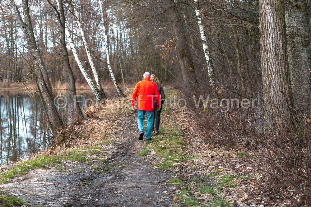 A man and a woman walk along a path in the woods.