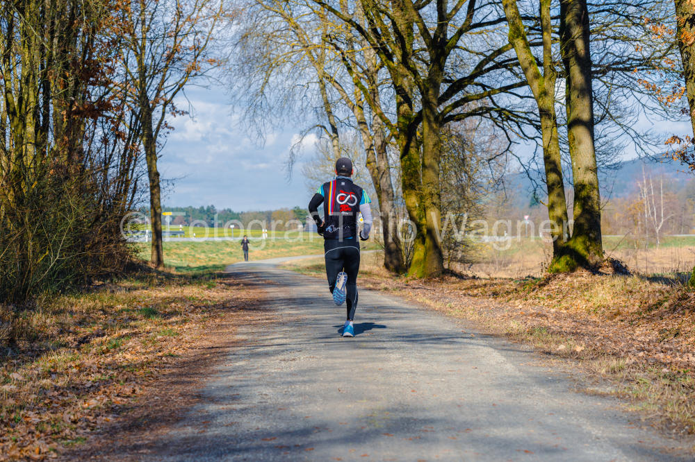 Athlete running on a country road in sunny autumn day.