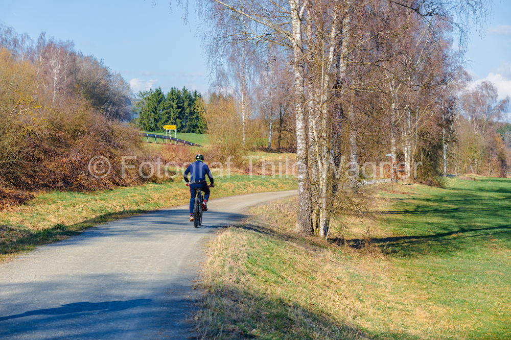 Rear view of a cyclist running on a rural road in the countryside