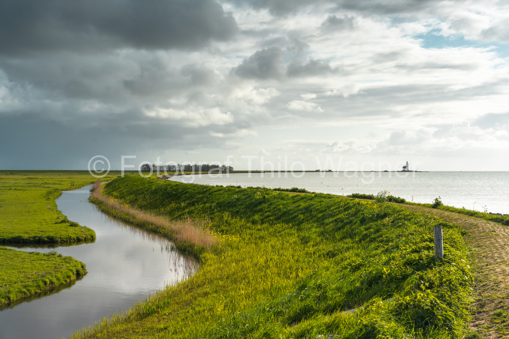 Dike along the shore of a lake under a stormy sky near Marken on the IJsselmeer in the Netherlands. Municipality of Waterland in the province of North Holland.