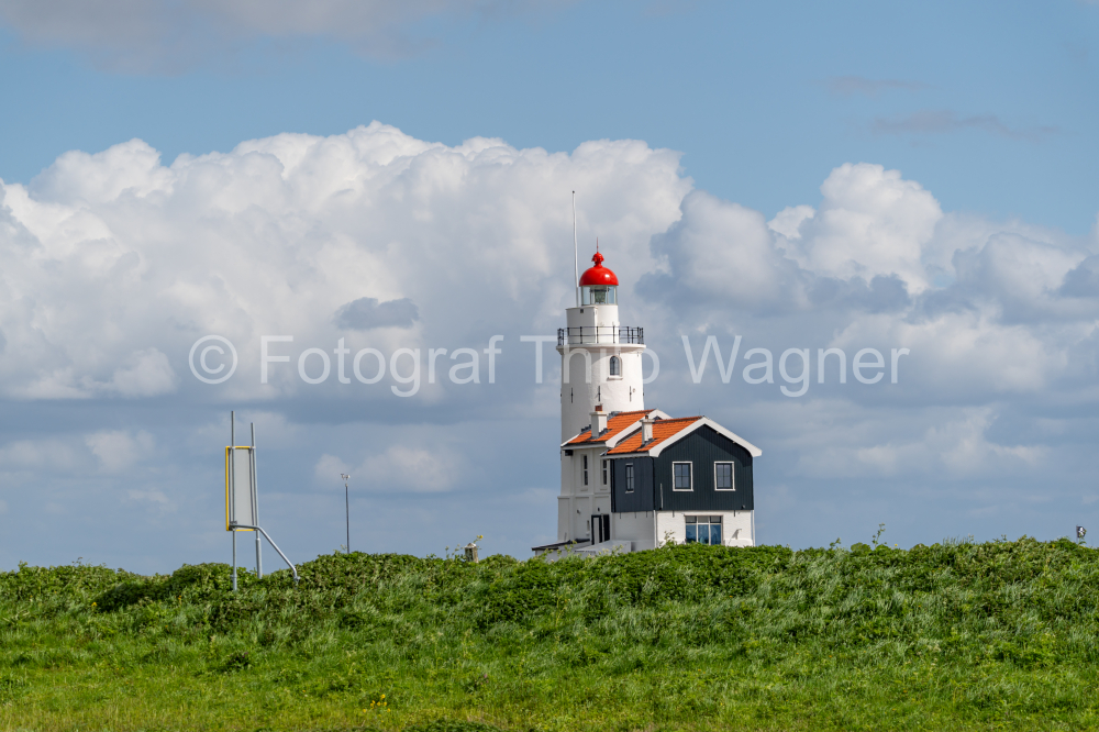 The Paard Van Marken lighthouse in spring with blue sky and clouds, Paard van Marken on the Dutch peninsula on the IJsselmeer, small village in the municipality of Waterland, North Holland, Netherlands.